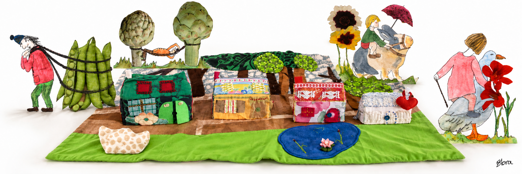 Les maisons en tissu de Barbara sur son tapis déployé au sol, entourées du porteur de petits pois, de la cavalière sur l’oie, du cavalier sur l’âne et du hamac entre les artichauts. Une seule signature Bbra.